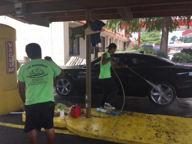 Las Banderas staff hand-washing a sedan at the wash bay
